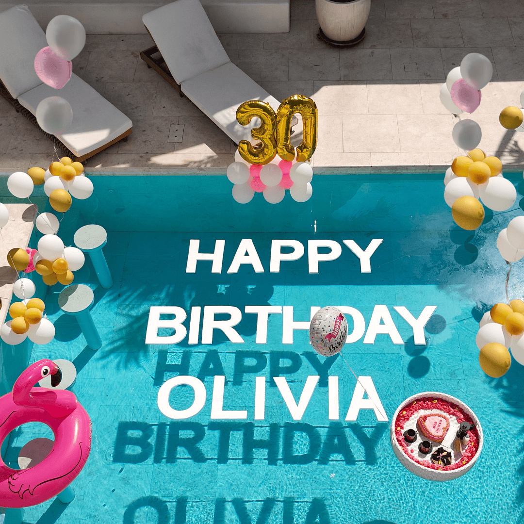 Birthday surprise package in Bali with custom pool message, birthday balloons, floating cake, rose bouquet, and villa decorations.